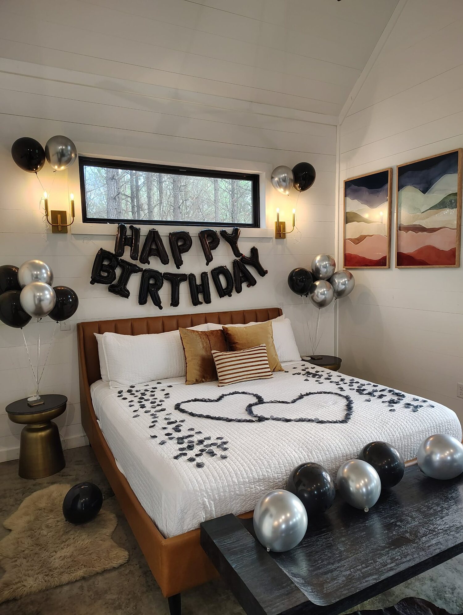Birthday setup with balloons and rose petals staged on a king bed at The Vine cabin