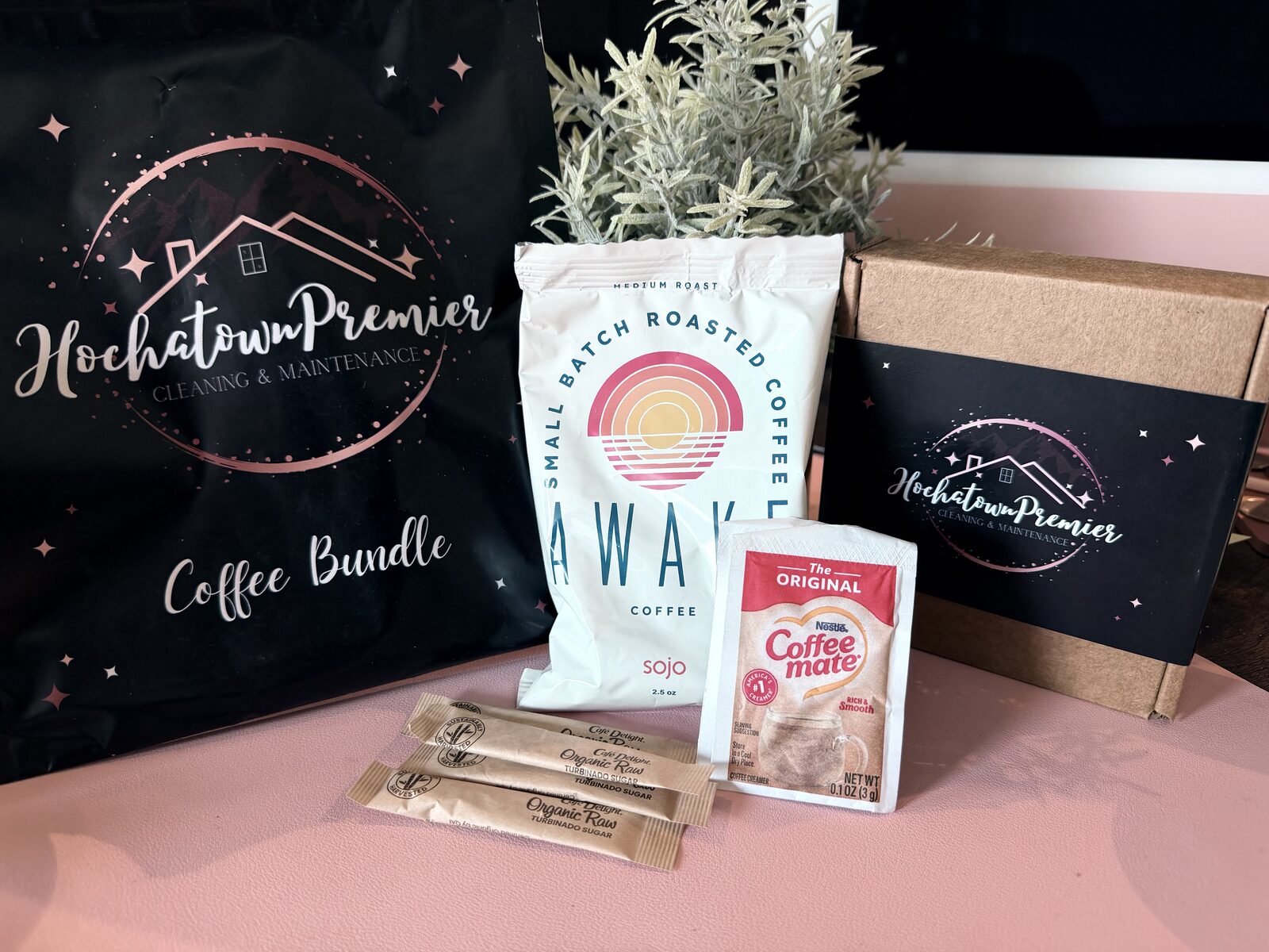 Coffee Bundle contents laid out beside the pouch — a bag of small-batch roasted coffee, a creamer packet and raw sugar sticks