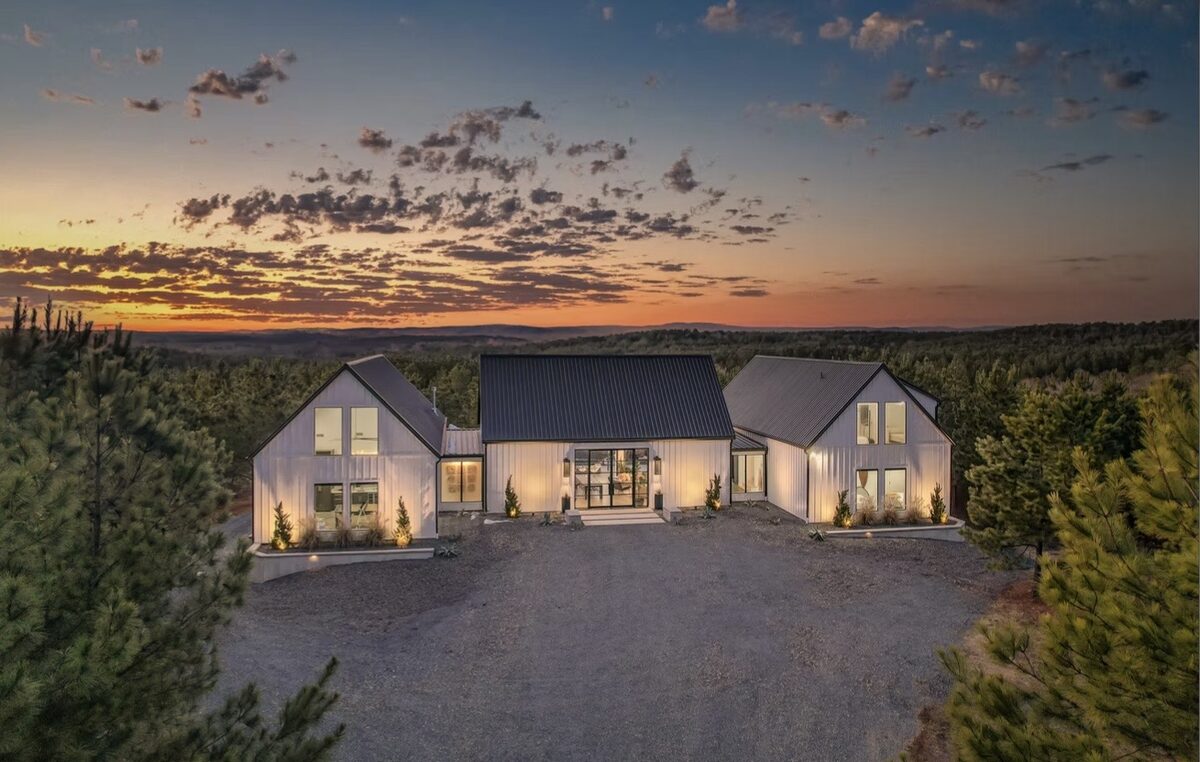 The Vineyard — a white modern farmhouse cabin lit at sunset above a gravel drive