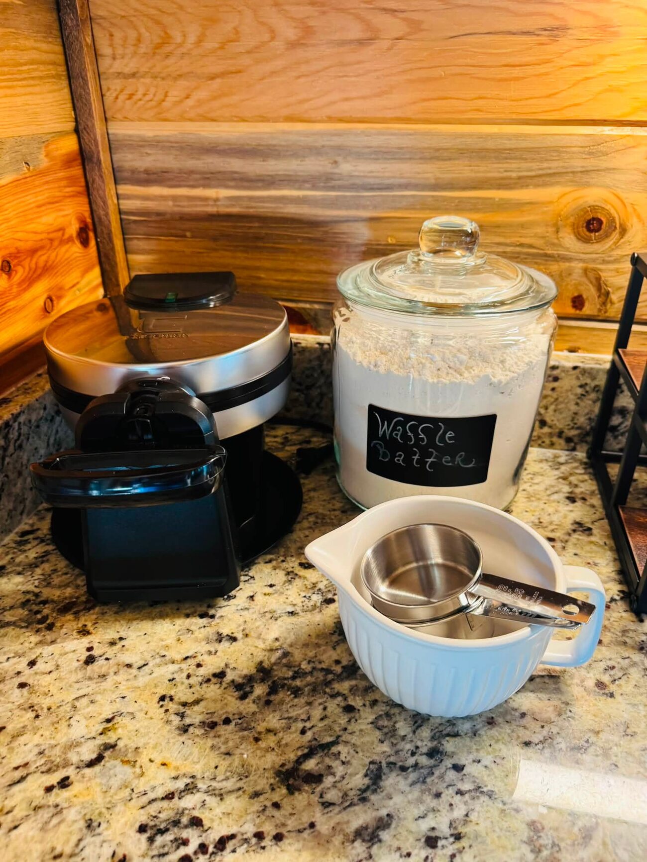 Waffle maker, glass Waffle Batter jar, and measuring cups styled on a granite counter